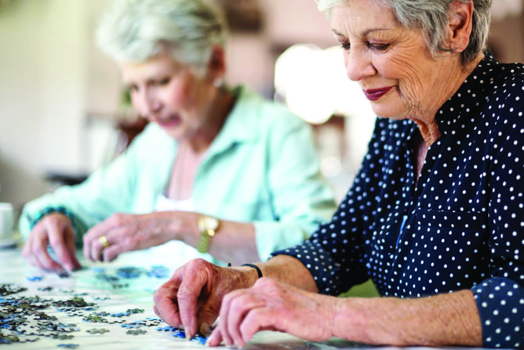 Two women building a puzzle.