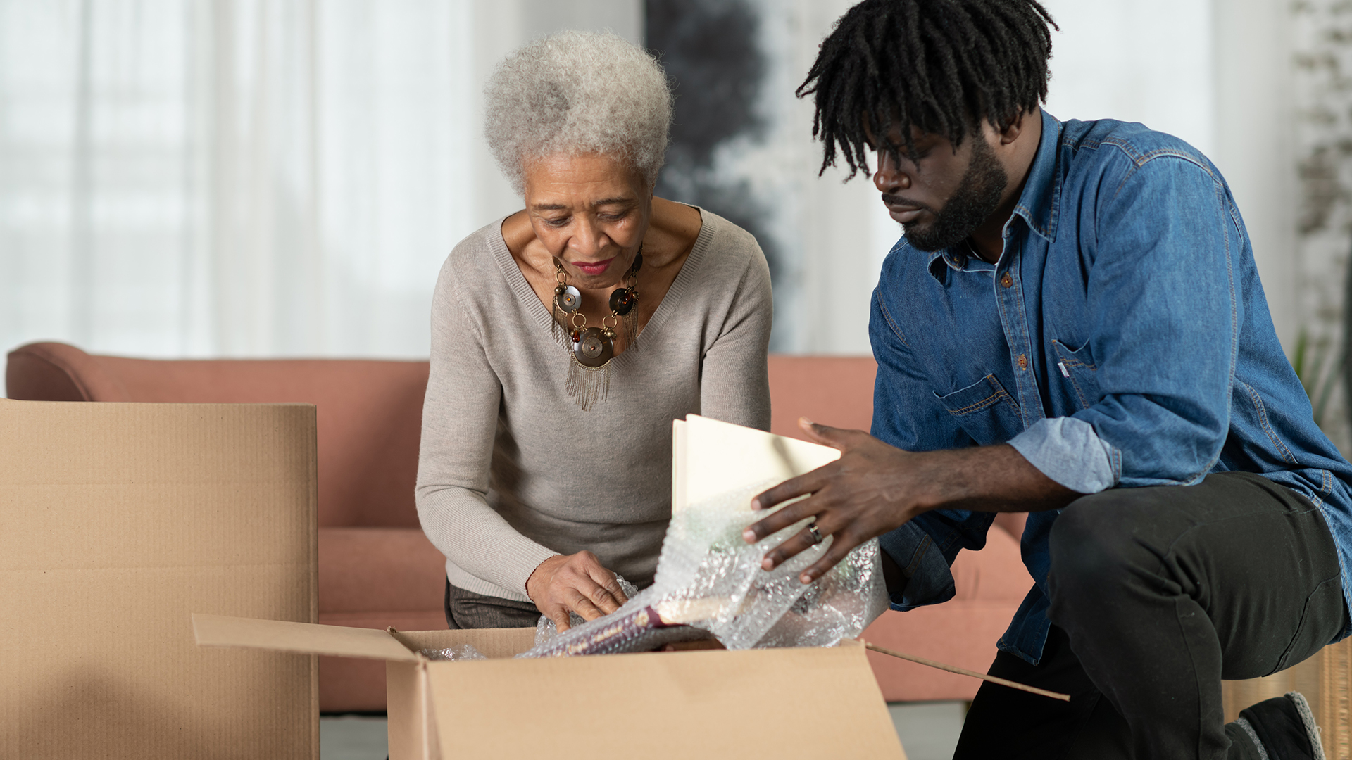 A senior mother and her adult son unpacking boxes