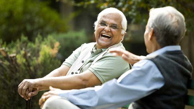 senior men sitting outside laughing together